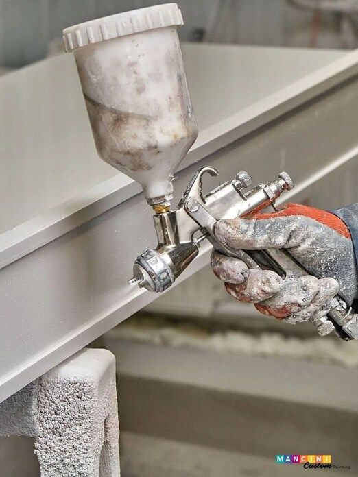 A house painting contractor using a spray gun on a piece of a cabinet.