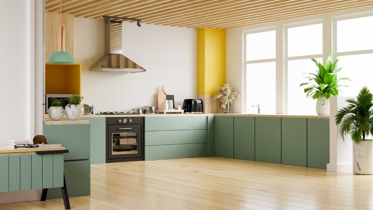 A kitchen with green cabinets , a stove , and a lot of windows.