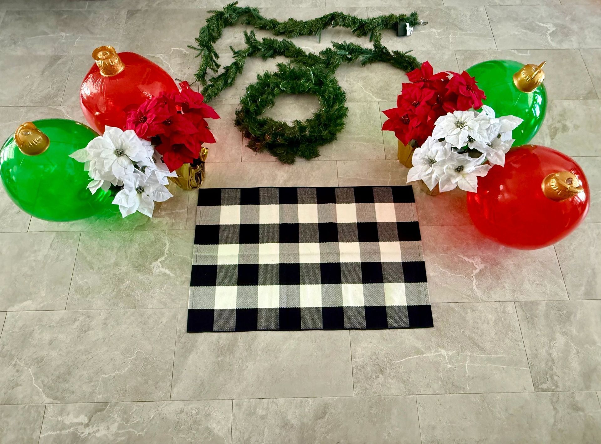 Christmas decorations: Large red and green ornaments with poinsettias, garland, and a buffalo check rug.
