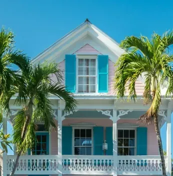 Pink house with turquoise shutters and palm trees.