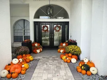Front porch decorated with pumpkins, mums, and wreaths for fall.