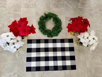 Christmas decor: red and white poinsettias, green wreath, black and white checkered rug on floor.