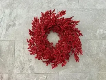 Red sparkly wreath on a gray tiled wall.