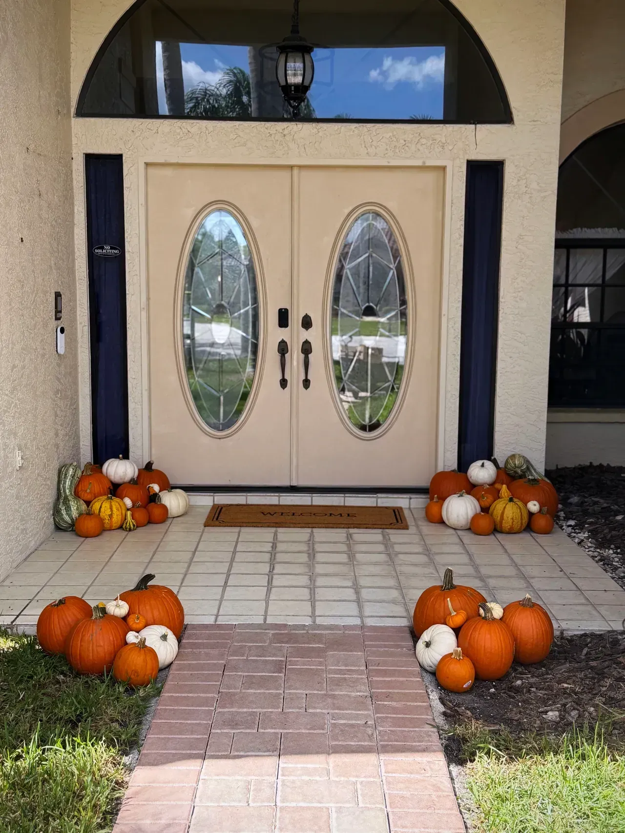 Front door decorated with pumpkins. Orange and white pumpkins surround the entrance.
