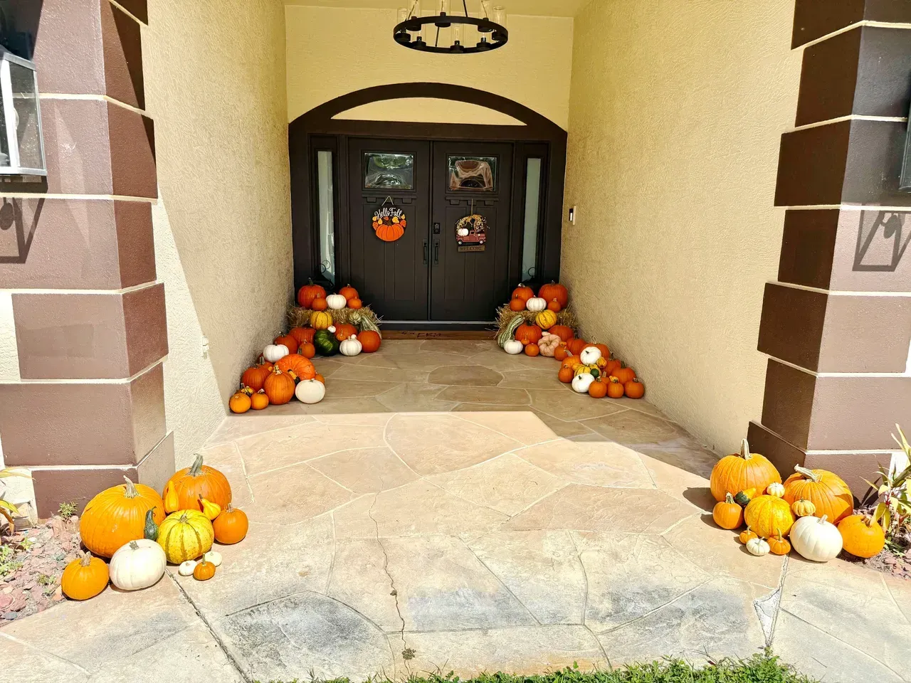 Entrance decorated for fall with pumpkins and gourds in various colors. Brown door.