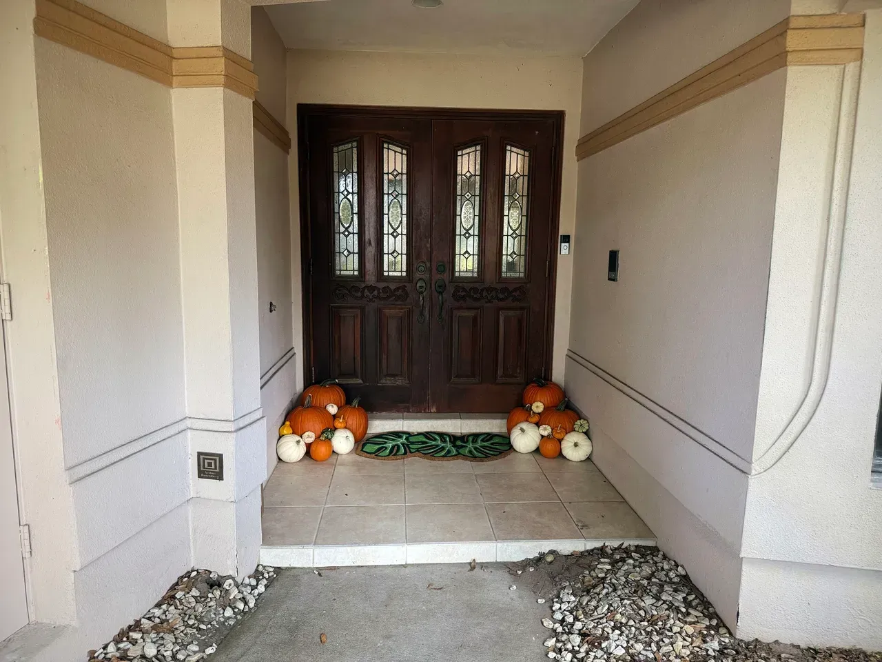 Wooden double doors flanked by pumpkins, stone entrance, and decorated walls.