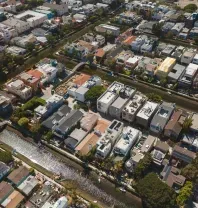 Aerial view of residential neighborhood with canals. Houses with varying roof colors line waterways.