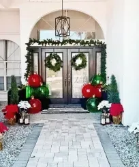 Christmas-decorated front entrance with red and green ornaments, wreaths, and poinsettias.