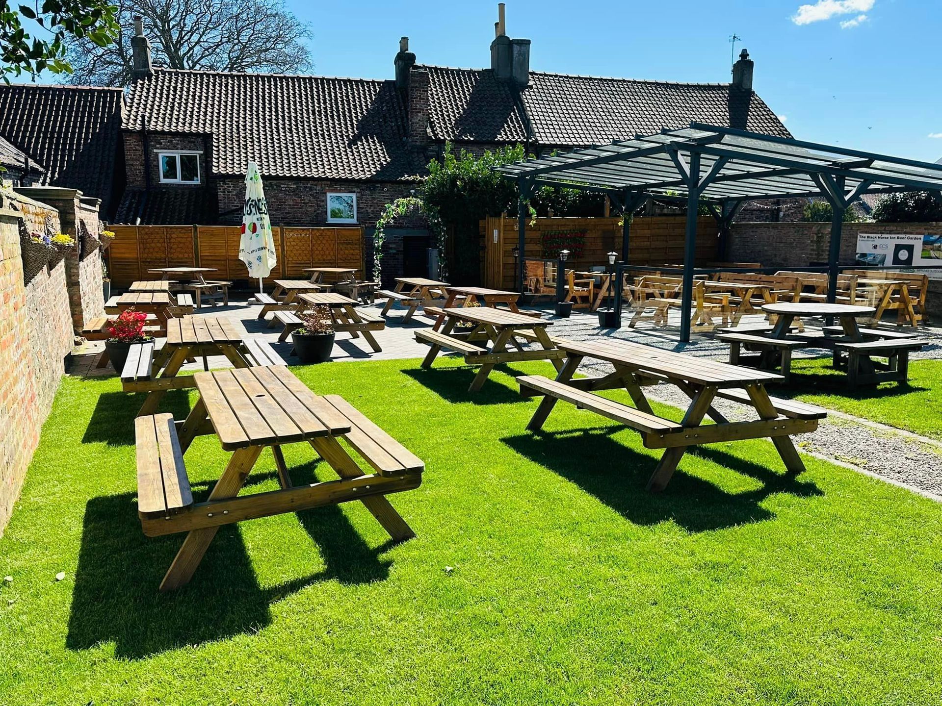 A picnic area with wooden tables and benches in front of a building.
