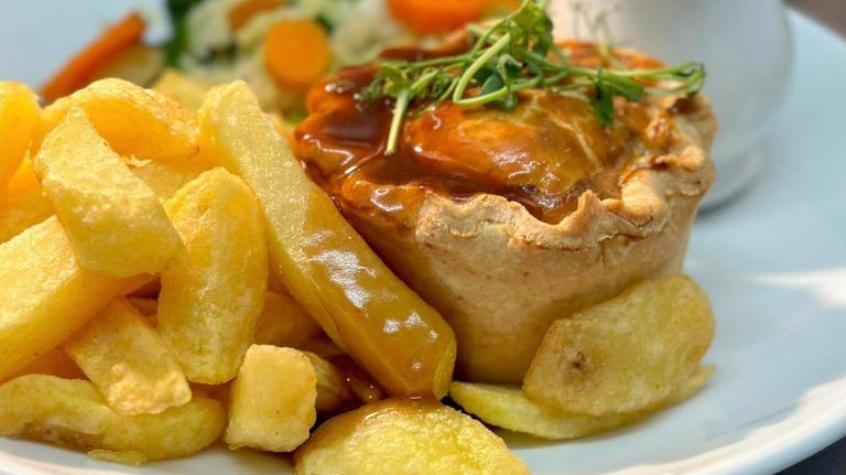 A white plate topped with a pie and french fries.