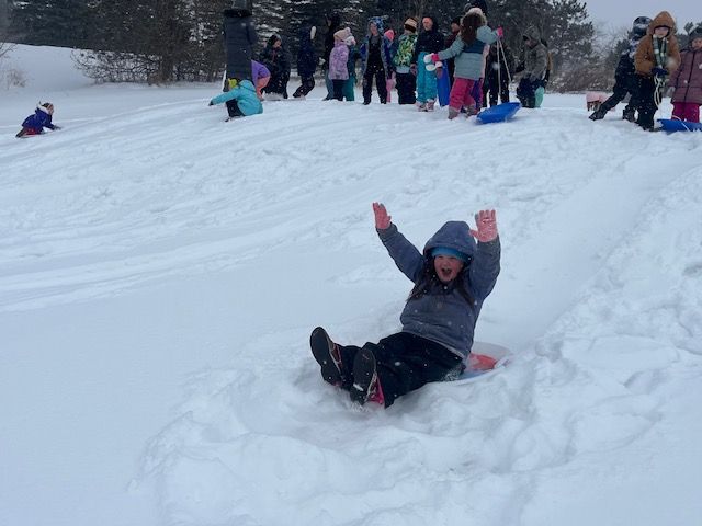 Elementary student sledding down a hill