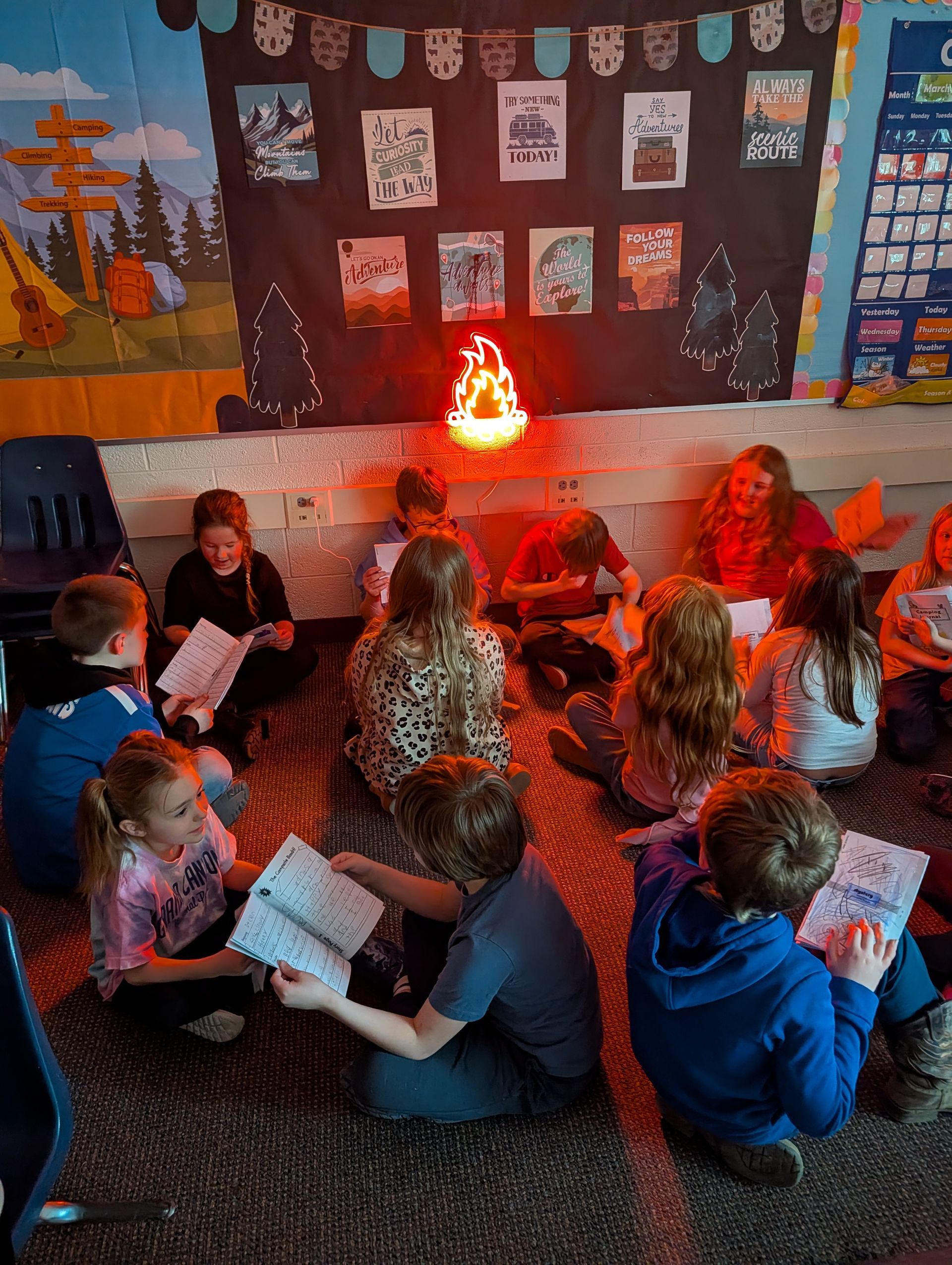 Students reading books around a fake campfire light for March is Reading Month