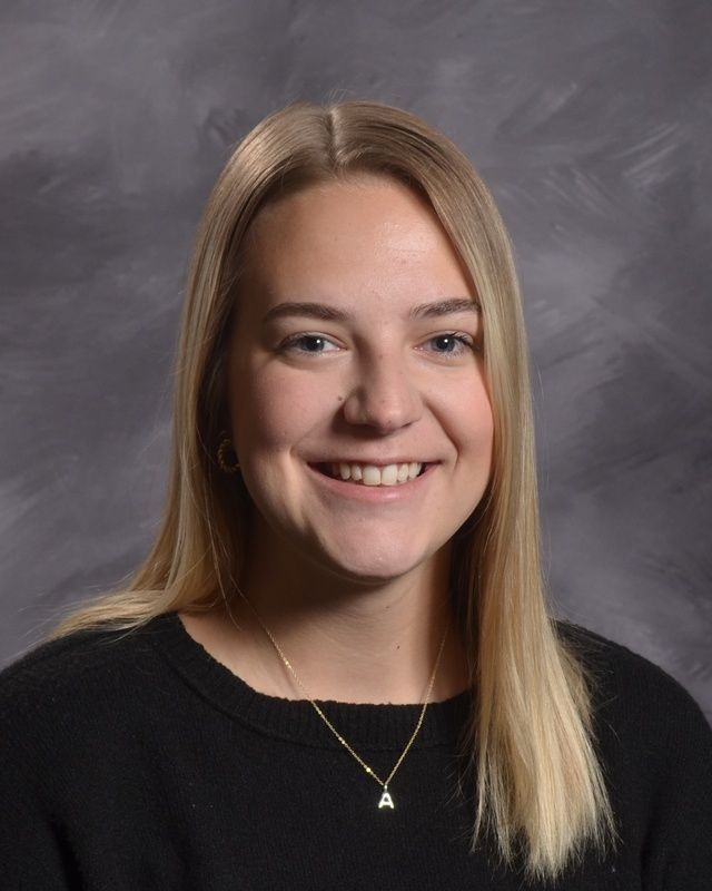 A woman with long hair wearing a black shirt smiling for the camera