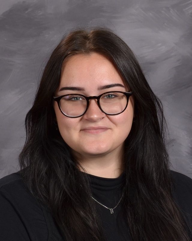 A woman wearing glasses and a black shirt is posing for a picture.