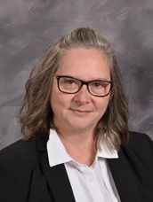 Woman wearing glasses and a black suit jacket posing for camera