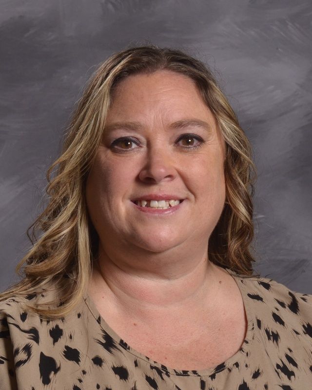 A woman with long hair and wearing a printed sweater smiling for the camera