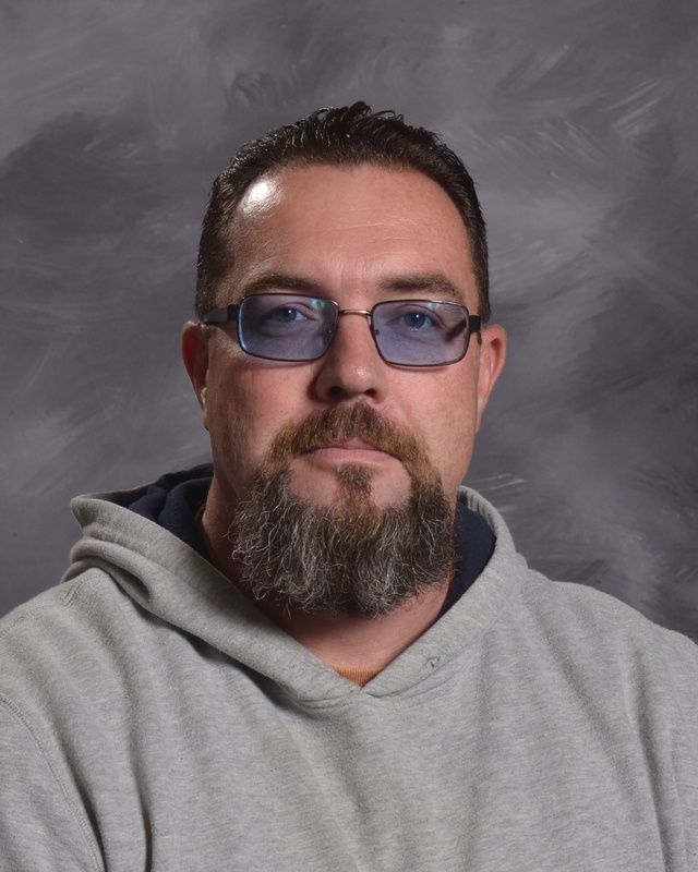 A man with a beard wearing a grey hoodie posing for the camera