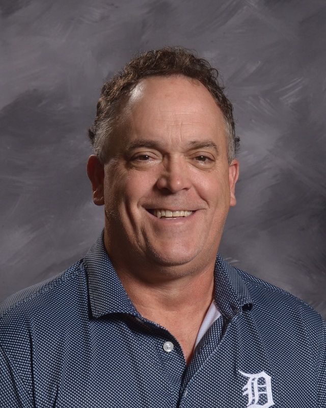 A man in a dark grey shirt is smiling for the camera