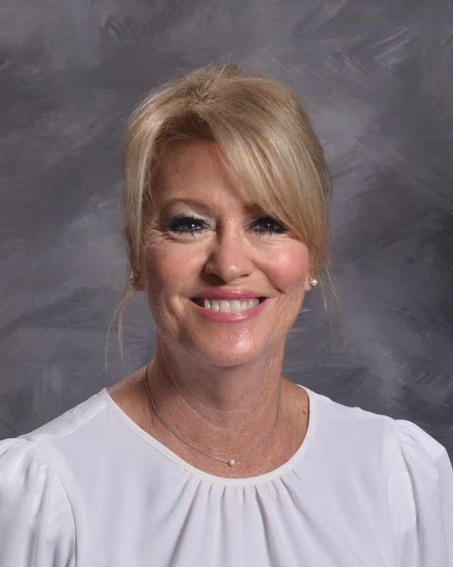 A woman in a white shirt is smiling for the camera