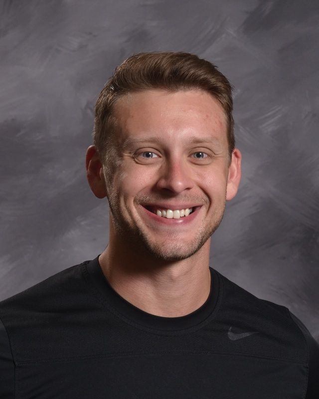 A man wearing a black t-shirt smiling for the camera