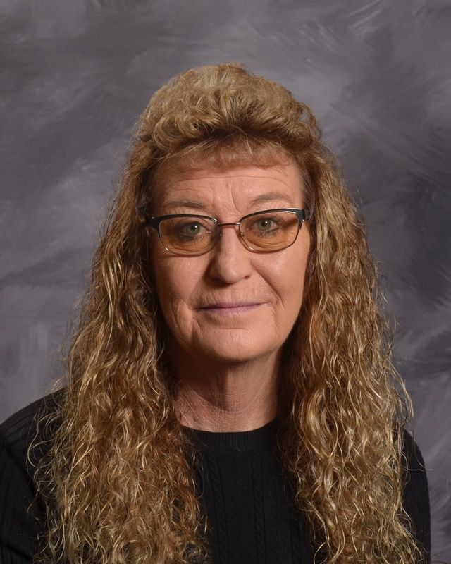 A woman wearing glasses and a black sweater poses for a picture