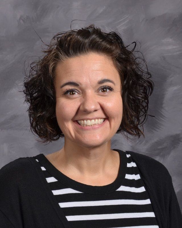 A woman wearing a black and white striped shirt smiles for the camera