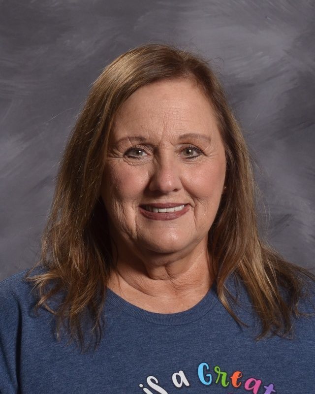 A woman wearing a blue shirt & smiling for the camera