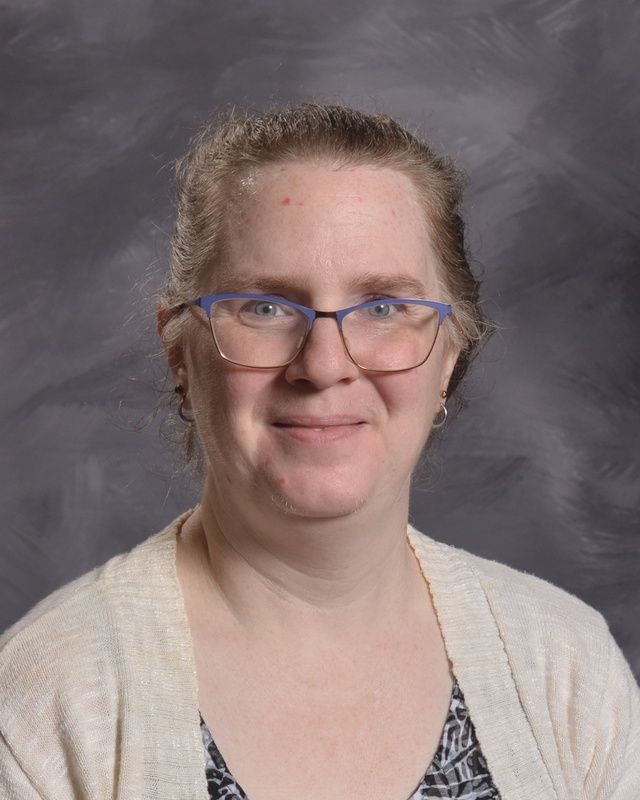 Woman with long hair and glasses smiles for the camera