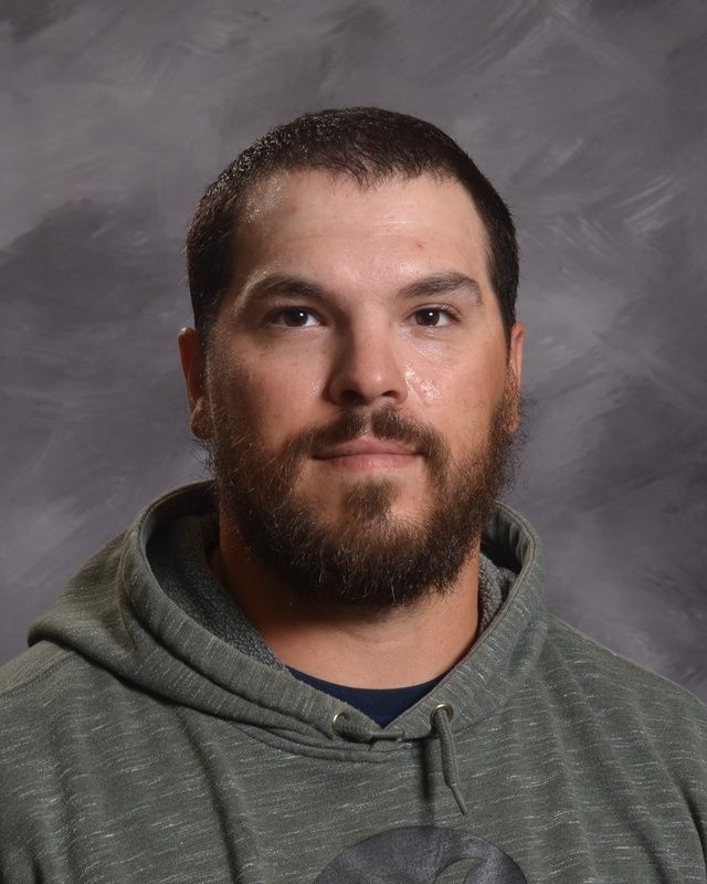 A man with a beard wearing a grey hoodie posing for the camera