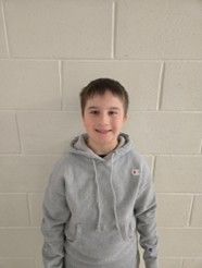 A young boy wearing a grey hoodie smiling for the camera