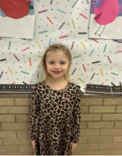 A young girl wearing a leopard print shirt smiling for the camera