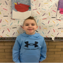 A young boy wearing a light blue hoodie smiling for the camera
