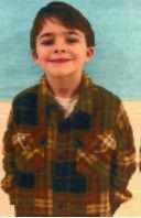 A young boy in a Grey t-shirt smiling for the camera