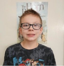 A young girl wearing a black t-shirt and glasses smiling for the camera