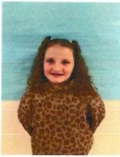 A young boy wearing a grey hoodie smiling for the camera