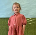 A young girl wearing a red dress smiling for the camera