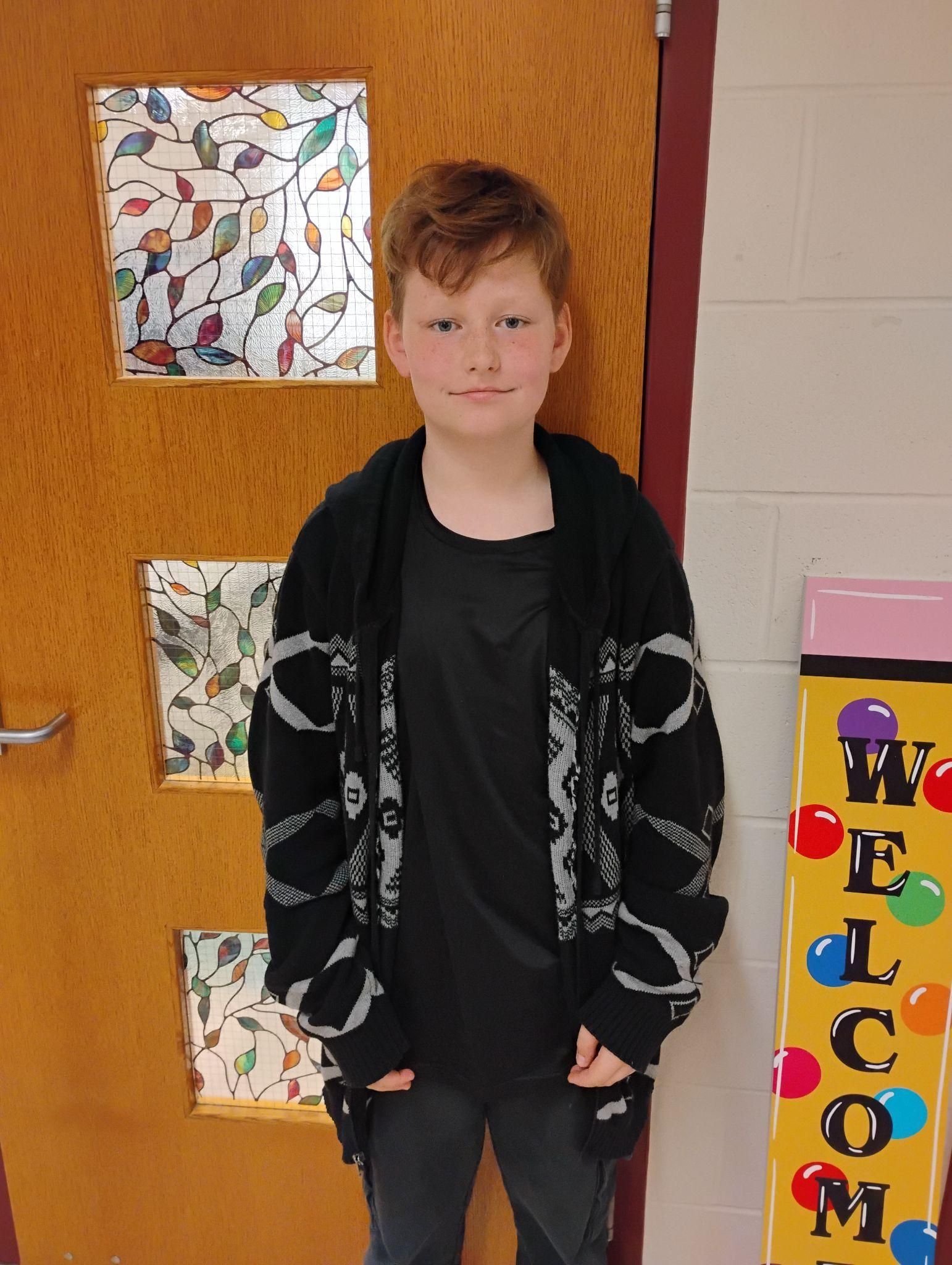 Young boy wearing a black hoodie smiling for the camera