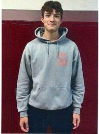 A boy wearing a grey hoodie smiling for the camera