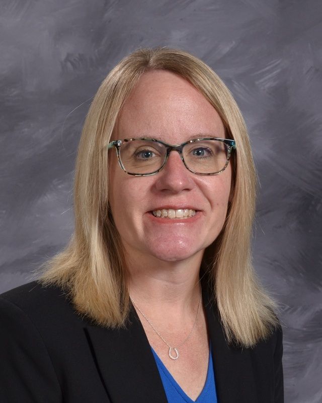 Women with short blonde hair and glasses smiling for the camera