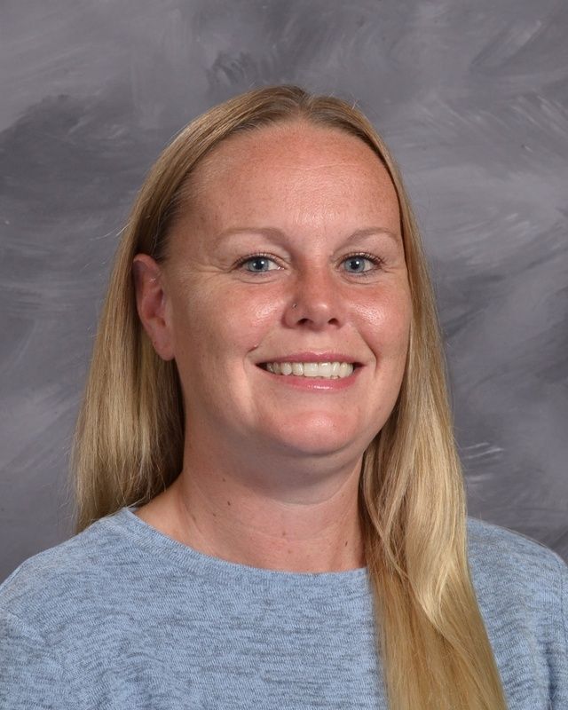 A woman in a blue sweater is smiling for the camera