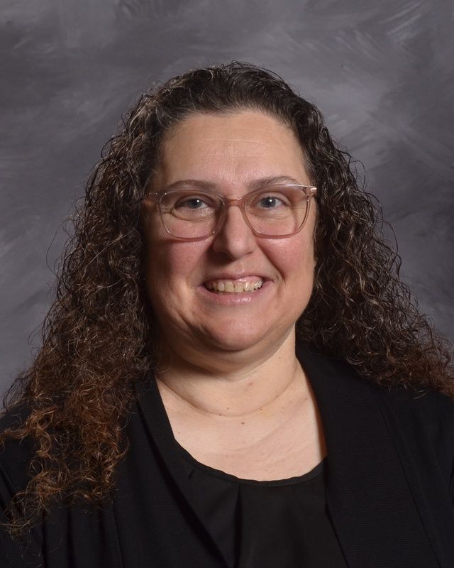 A woman wearing glasses and a black shirt smiles for the camera