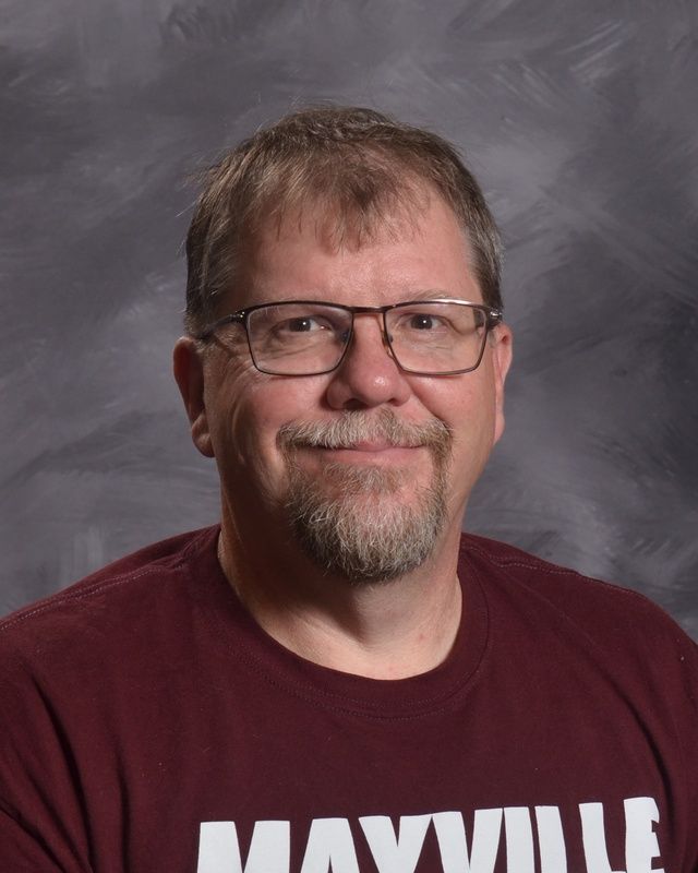 A man with glasses and a beard is smiling for the camera