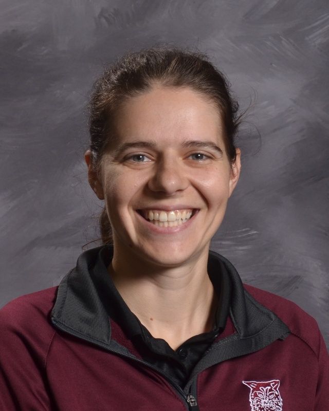 A woman wearing a maroon shire smiling for the camera