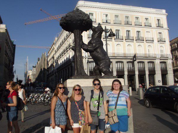 A group of women standing in front of a statue of a bear holding a tree