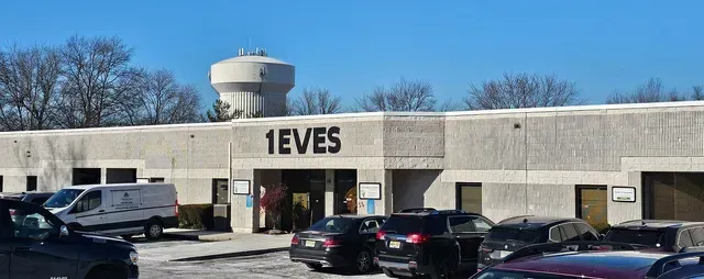 A building with a water tower in the background and cars parked in front of it.
