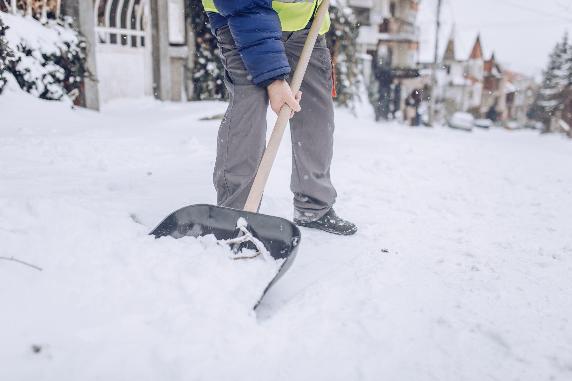 A man is shoveling snow on a sidewalk with a shovel.