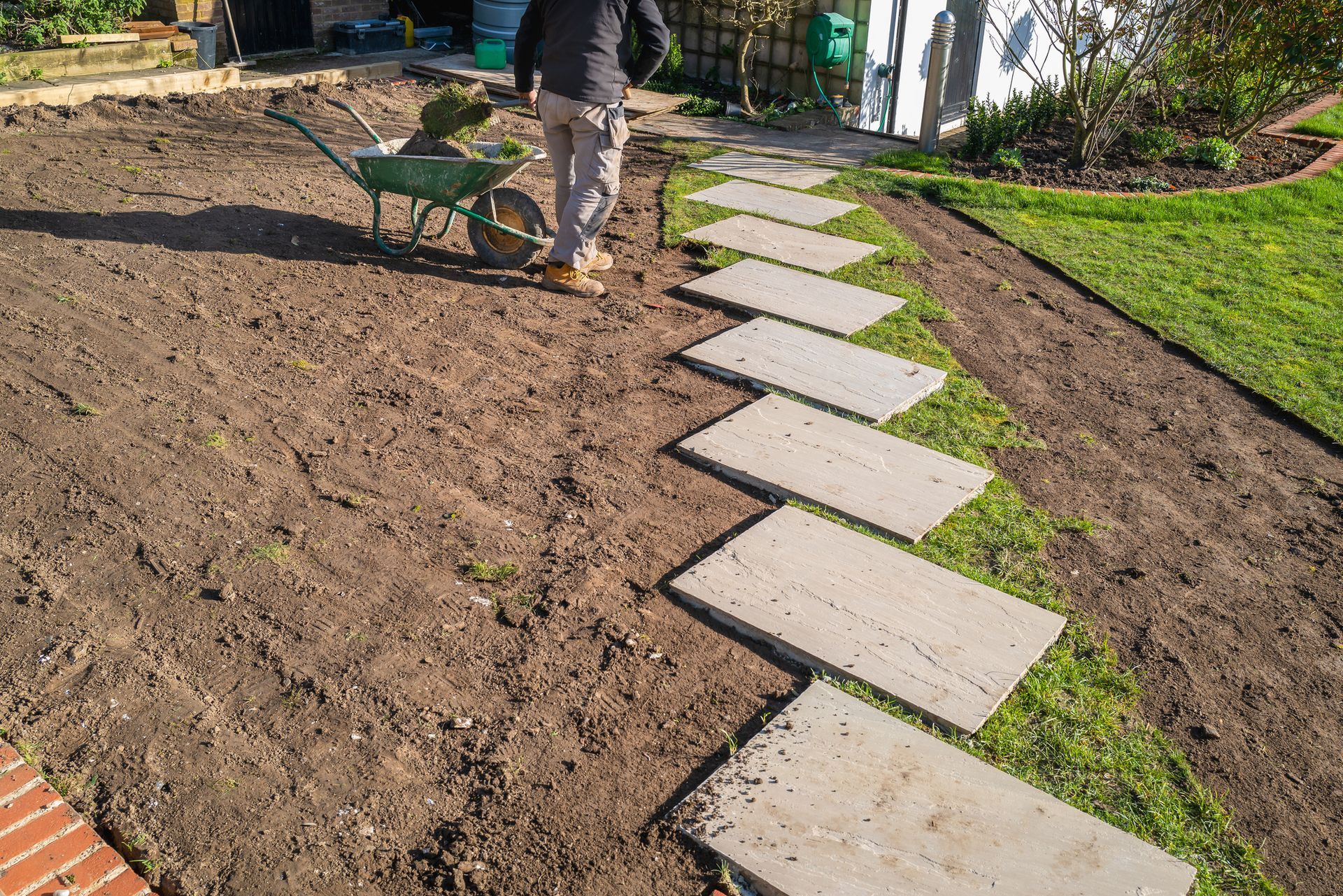 A man is pushing a wheelbarrow down a path.