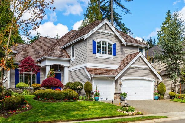 A large house with blue shutters and a white garage door is sitting on top of a lush green lawn.