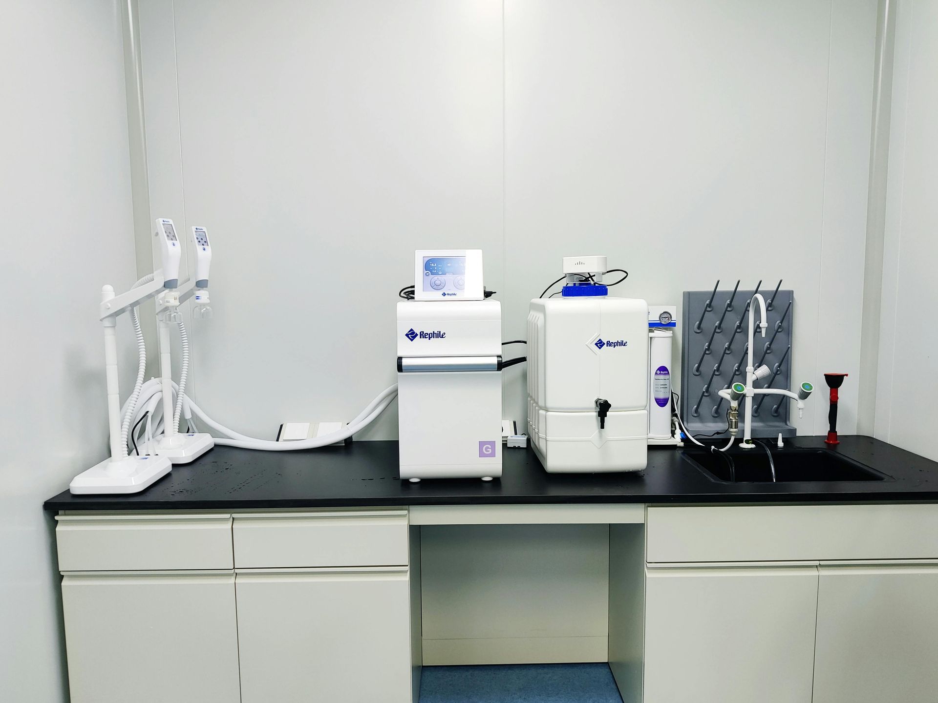 Laboratory bench with medical equipment, white walls, and black countertop surface.