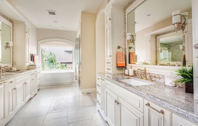 A bathroom with two sinks , two mirrors and a bathtub.